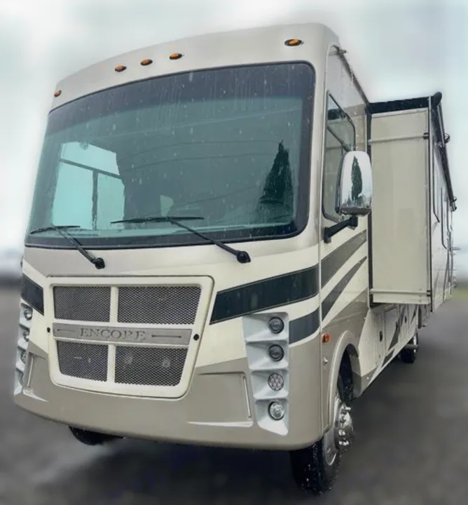 Front-left exterior view of a modern beige and black RV rental motorhome with a side slide-out extended.. Coachmen Encore 2021
