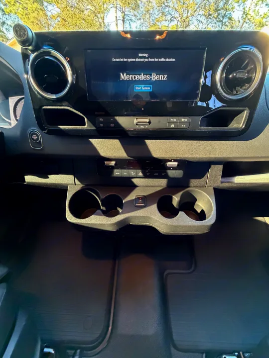 Inside an RV rental: Mercedes-Benz Sprinter dashboard with infotainment, climate controls, and cupholders.. Cahaba Cahaba Class B 2022