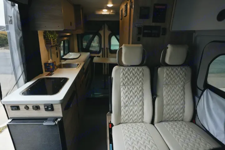 Inside a stylish RV rental, featuring a compact kitchen with cooktop, sink, fridge, and plush seating.. Winnebago Winnebago 2026