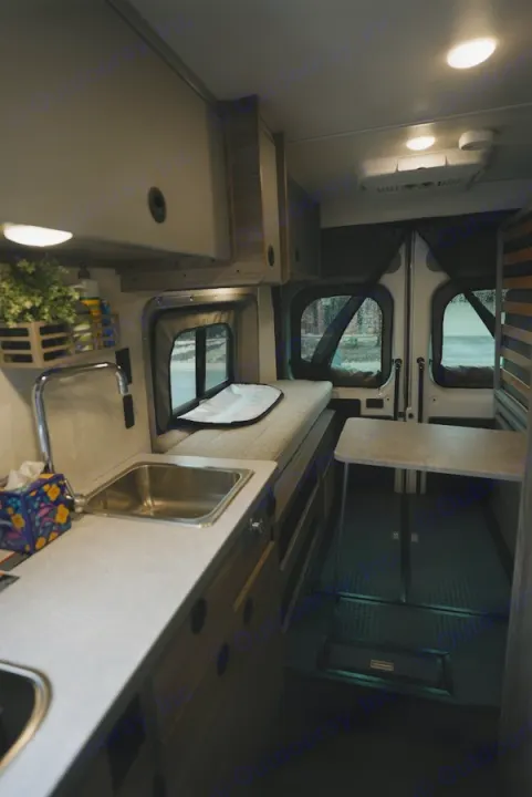 Inside a modern rv rental campervan, featuring a well-equipped kitchenette, bench seating, and convertible table space.. Winnebago Winnebago 2026