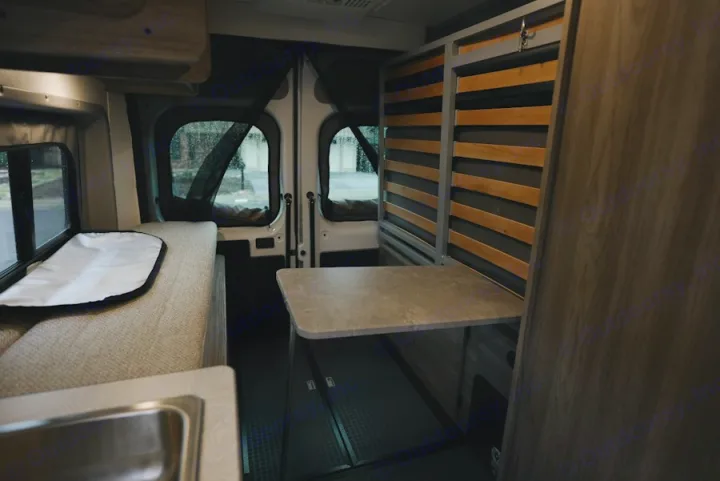 RV rental interior: cozy camper van with convertible bench bed, fold-down table, and a small sink for mobile living.. Winnebago Winnebago 2026