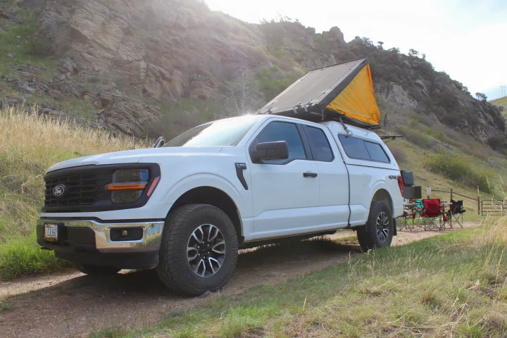 White Ford F-150 4x4 truck with a rooftop tent & camping setup. Perfect for an 'rv rental' adventure in rocky terrain.. Ford Ford F150 2024