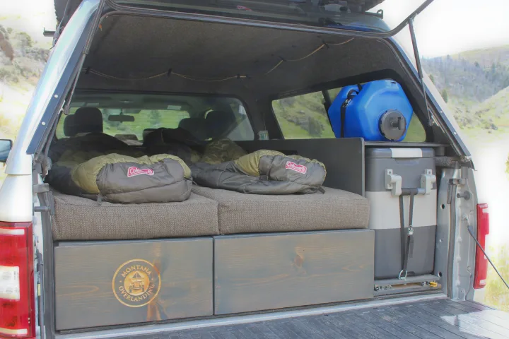 RV rental ready: Truck bed camper setup with sleeping platform, Coleman bags, cooler, and water for overlanding.. Ford Ford F150 2024