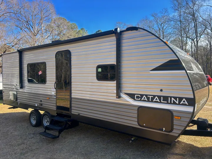 A gray and black Catalina travel trailer (RV) with steps, dual axles, and an awning roller. Perfect for your next RV rental trip.. Coachmen Catalina 2025