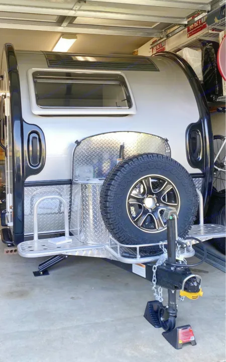 Sleek teardrop RV rental parked indoors. Notice the rear spare tire, diamond plate details, and robust hitch system.. nuCamp T@B 2022