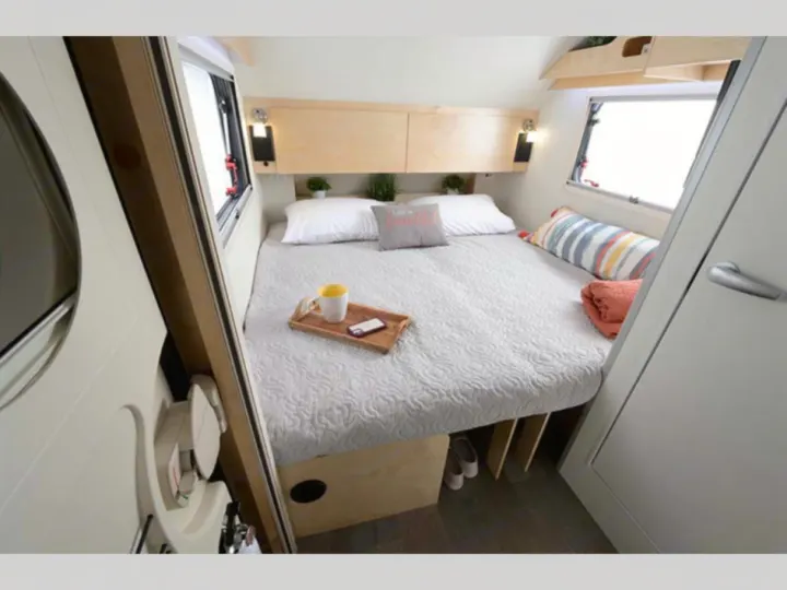 Compact, well-appointed RV rental bedroom. Features a comfy bed with overhead storage, windows, and under-bed space.. nuCamp T@B 2022