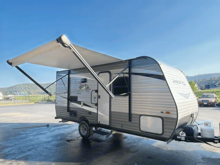 This Jayco Jay Flight SLX travel trailer rv rental with its awning extended, parked on wet pavement, ready for adventure.. jayco Jay Flight 2020