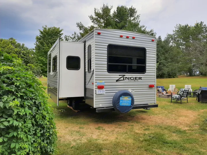 Enjoying an RV rental: a Zinger travel trailer with its slide-out extended, parked on grass near a fire pit.. Crossroads RV Zinger 2017