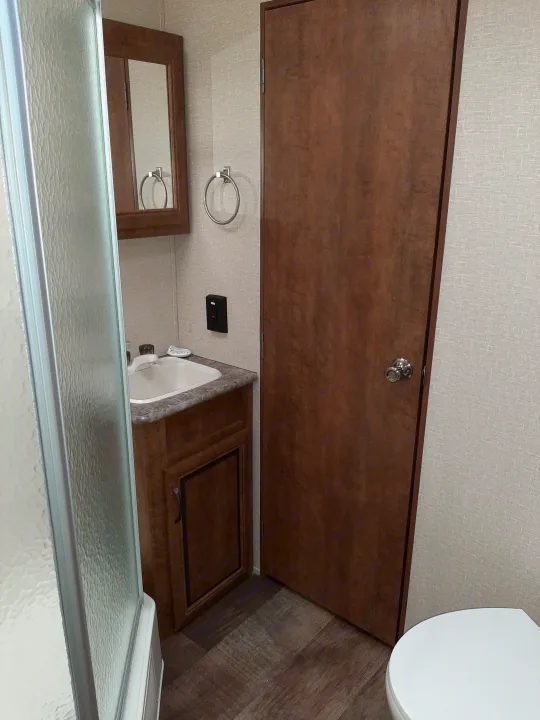 Functional RV rental bathroom: shower, sink vanity with mirror, and toilet, offering essential amenities.. Crossroads RV Zinger 2017