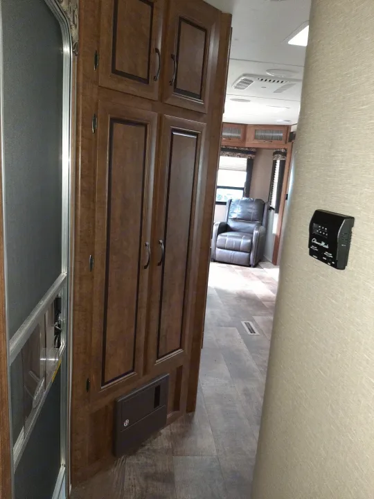 RV rental interior: wood cabinets, comfy recliner, and a thermostat on the wall. Ready for your next journey.. Crossroads RV Zinger 2017