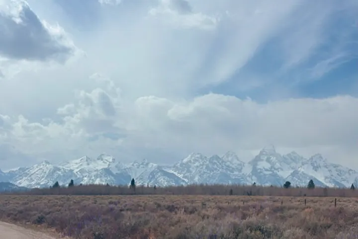 Majestic snow-capped mountains rise above vast plains under a cloudy sky. Rent an RV and explore this breathtaking national park landscape.. Thor Scope 2024