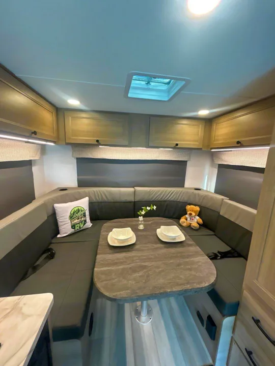 Comfortable U-shaped dinette in an rv rental, perfect for meals & relaxation. Features overhead cabinets & skylight.. Forest River Sunseeker 2027