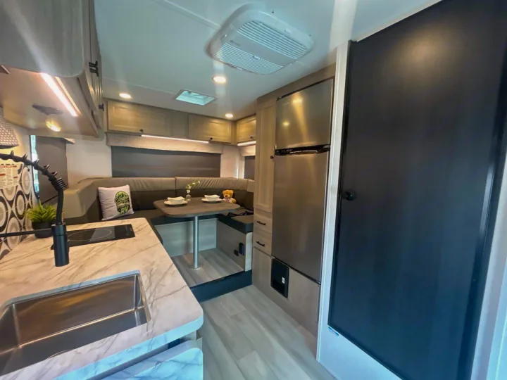 Clean rv rental interior featuring a modern kitchen, dinette, refrigerator, and ceiling AC unit.. Forest River Sunseeker 2027