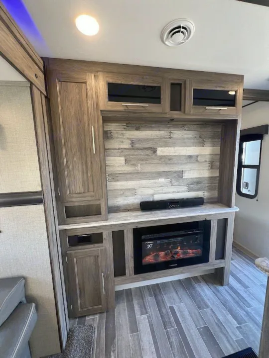 This RV rental's modern interior features a wooden entertainment center with an electric fireplace, soundbar, and storage cabinets.. Crossroads RV Zinger 2021
