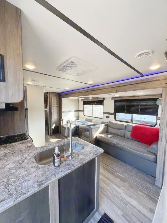 Spacious RV rental interior featuring a modern kitchen island, comfortable sofa, and dinette area.. Crossroads RV Zinger 2021