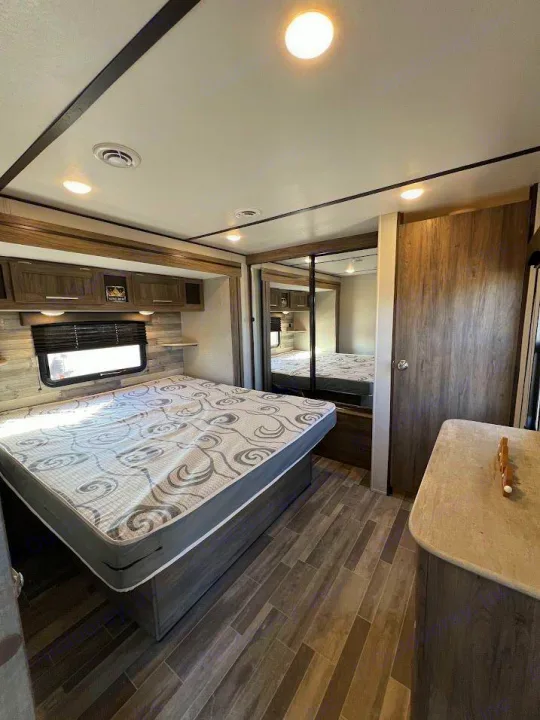Enjoy comfort in this modern RV rental bedroom. Features a large bed, ample storage, and mirrored wardrobe.. Crossroads RV Zinger 2021