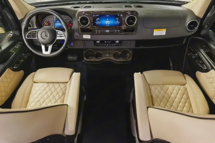 Inside a premium RV rental: Mercedes dashboard, large infotainment display, wood accents, and plush cream quilted seats.. Ultimate Toys Ultimate Coach 2024