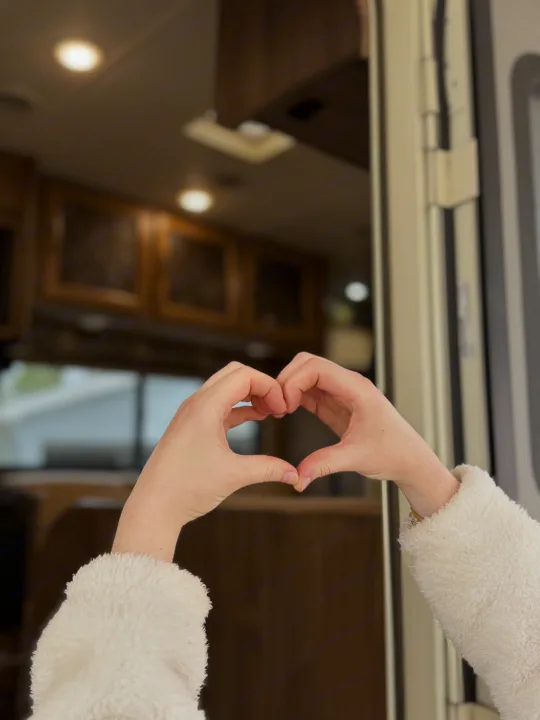 Heart-shaped hands inside a modern RV rental, featuring warm lighting and wood accents, perfect for a cozy trip.. Coachmen Freelander 26 RS 2017