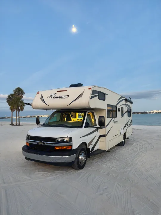 Enjoy an RV rental! White Coachmen Freelander parked on a sandy beach with palm trees, ocean views, and a moon in the sky.. Coachmen Freelander 26 RS 2017