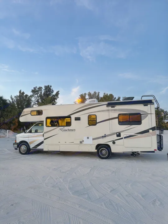 A Coachmen Freelander rv rental is parked on sandy ground with tire tracks under a twilight sky. Ideal for beach travel.. Coachmen Freelander 26 RS 2017