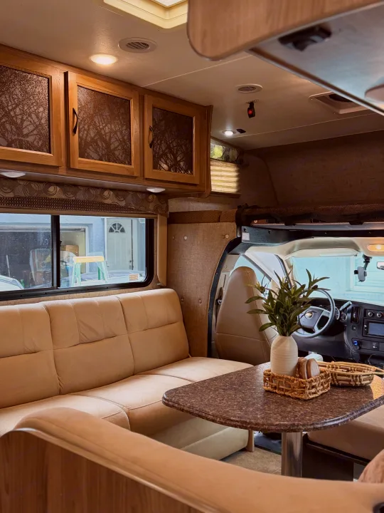 Cozy RV rental interior with light beige seating, a dinette, and cab view. Perfect for comfortable travel.. Coachmen Freelander 26 RS 2017