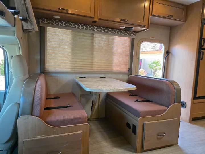 Enjoy this functional RV rental dinette featuring comfy bench seating with seatbelts, a table, and overhead cabinets. Ideal for travel.. Thor Daybreak 2020