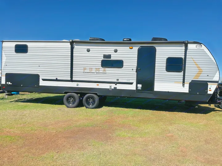 This Puma Camping Edition travel trailer, an excellent RV rental option, is parked on grass under a clear blue sky.. Forest River Palomino Puma Camping Edition 2025