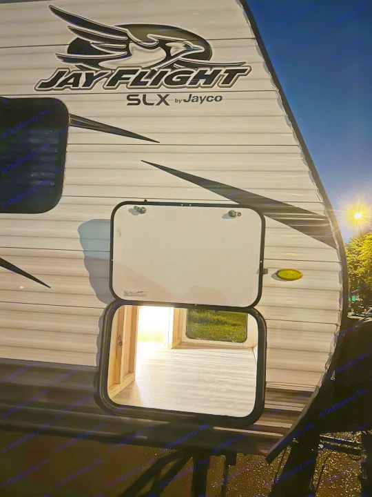 Night view of a Jayco Jay Flight SLX RV rental with an open, illuminated storage compartment, revealing interior access.. Jayco Jay Flight SLX 2018