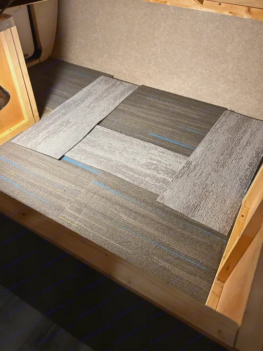 Carpet tiles being installed in an RV rental interior, showing dark and light grey patterns with blue accents.. Jayco Jay Flight SLX 2018