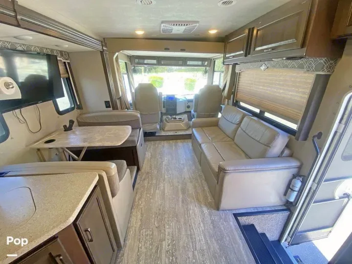 Spacious RV rental interior features a cozy living area with a couch, dinette, kitchen, and cockpit view.. Thor Hurricane 2017