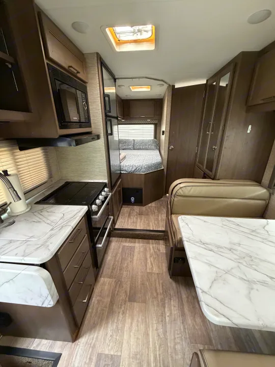 Interior view of RV rental: well-appointed kitchen, dinette, and bedroom. Modern design for comfortable travel.. Thor Coleman 2023