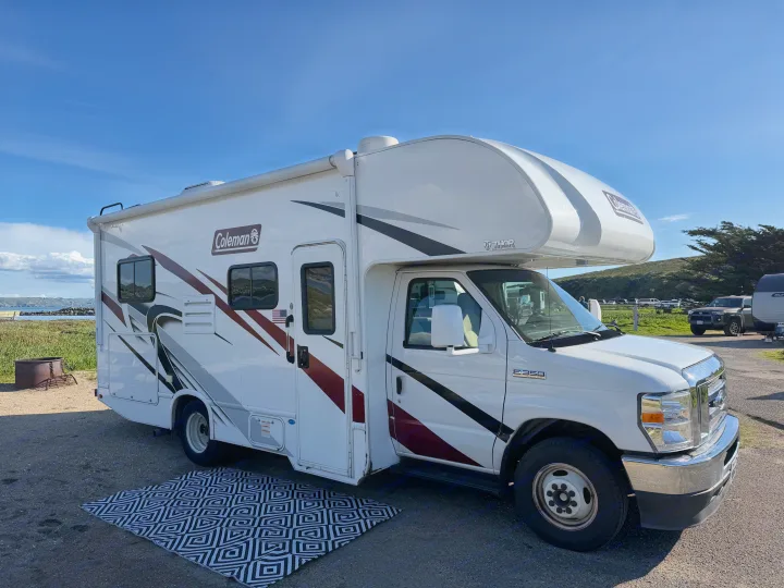 White Coleman RV rental parked at a coastal campsite with a view. Ideal for travel and outdoor adventures.. Thor Coleman 2023