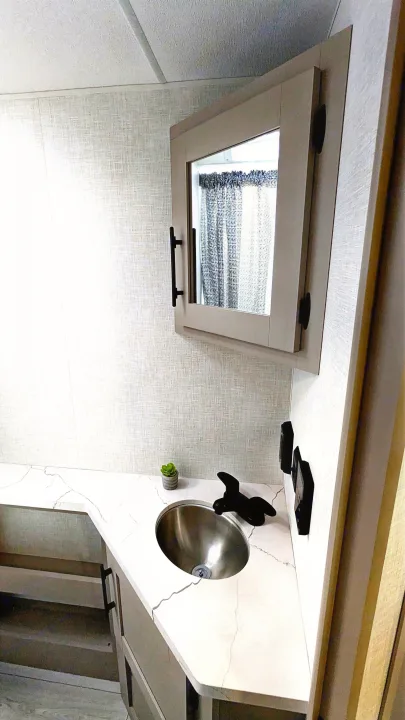 Modern RV rental bathroom featuring a compact vanity sink, marble-patterned countertop, and mirrored medicine cabinet.. KZ Connect SE 2025