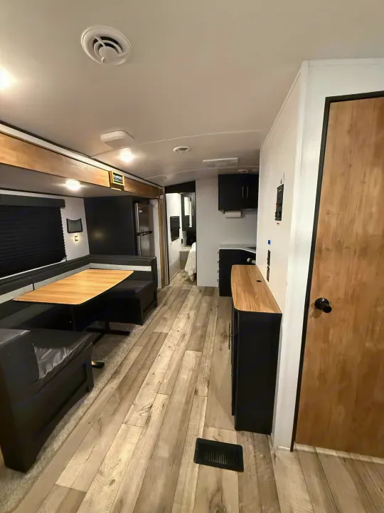 Step inside this modern RV rental featuring a comfortable dinette, functional kitchen, and stylish wood-look flooring.. Keystone RV Springdale 2022