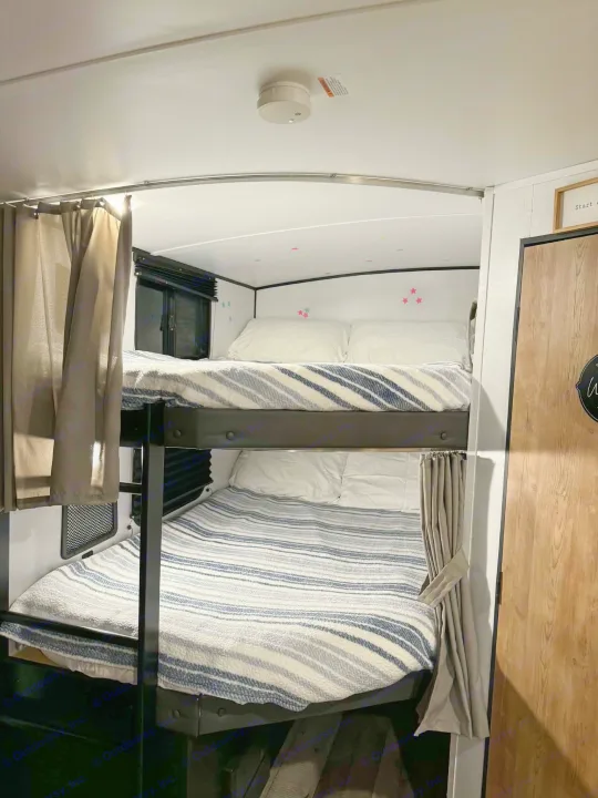 Cozy RV rental bunk beds with striped blankets, privacy curtains, and playful star decals. Perfect for travelers.. Keystone RV Springdale 2022