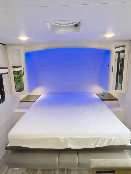 Cozy RV rental bedroom with a comfy bed, blue LED headboard lighting, mirrored cabinets, and ceiling lights.. Jayco Jay Feather Air 2025