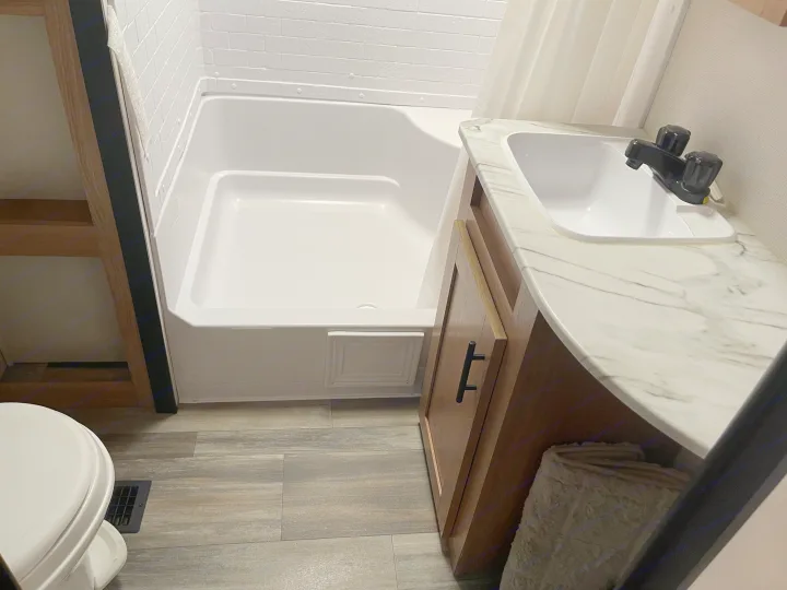 This RV rental bathroom features a clean white tub/shower, sink, toilet, and vanity with a marbled countertop.. Avenger Avenger Trailer 2022