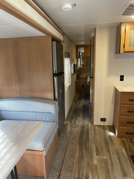 Step inside this modern **rv rental** showing a comfortable dinette, kitchen, and hallway with wood-look flooring.. Avenger Avenger Trailer 2022