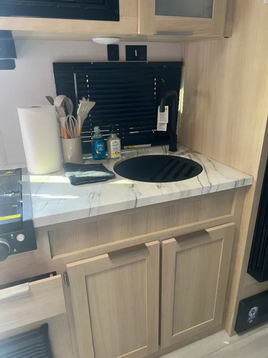 RV rental: well-equipped kitchen space with marble-look counter, black sink, and light wood cabinetry.. Forest River Salem FSX 2023