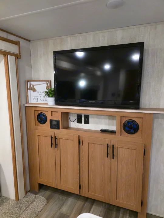 RV rental interior featuring a media console with TV, speakers, and light wood storage cabinets. Perfect for entertainment on the go.. Avenger LE 2022