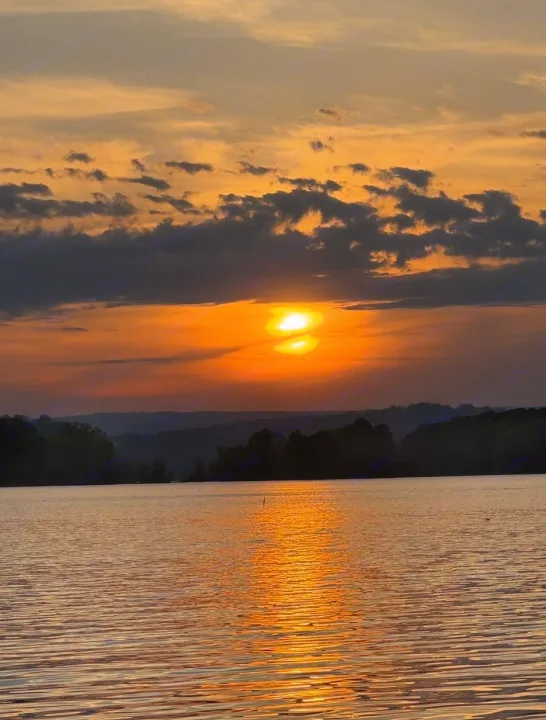 Stunning golden sunset over calm lake waters, with sun reflecting brightly. Imagine this view from your RV rental trip!. Forest River Salem 2024
