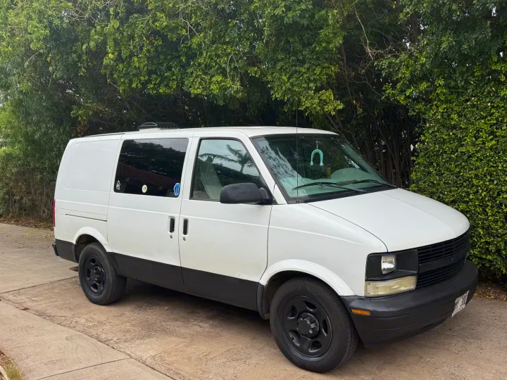 White Chevy Astro van, a perfect rv rental for van life, parked on a driveway with lush trees.. Chevrolet Other 2005