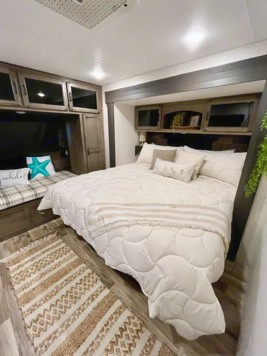 Stylish RV rental bedroom interior featuring a comfortable bed, accent pillows, and ample built-in storage.. Sporttrek Touring Edition 2024