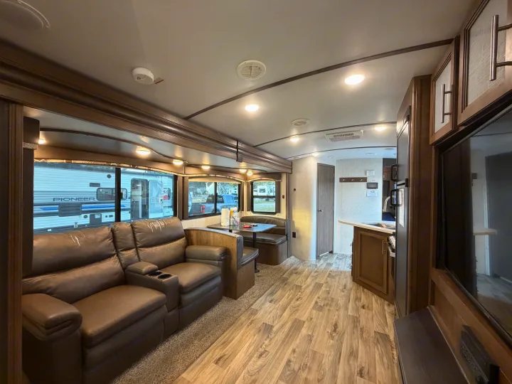 Bright RV rental interior showing a comfortable living area with recliners, dining booth, and compact kitchen.. Keystone Cougar Half-Ton 2020