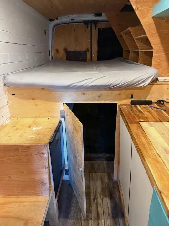 RV rental: Converted van interior featuring a comfortable bed, smart built-in storage, & compact kitchen amenities.. Ford Transit 2021