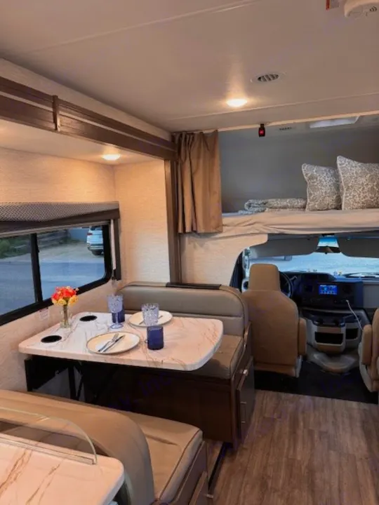 RV rental interior showcasing a dinette, side bunk, and an overhead bed, perfect for family travel.. Thor Four Winds 2025