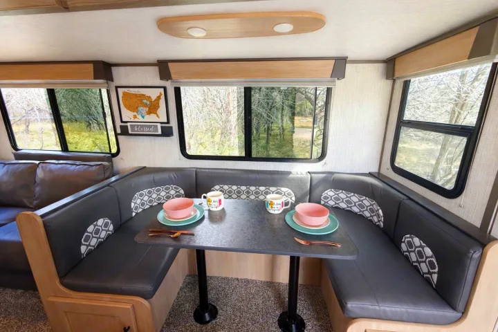 Interior of an RV rental: a modern dinette with U-shaped seating, a table set for two, and scenic windows.. Cruiser RV Radiance Ultra Lite 2020