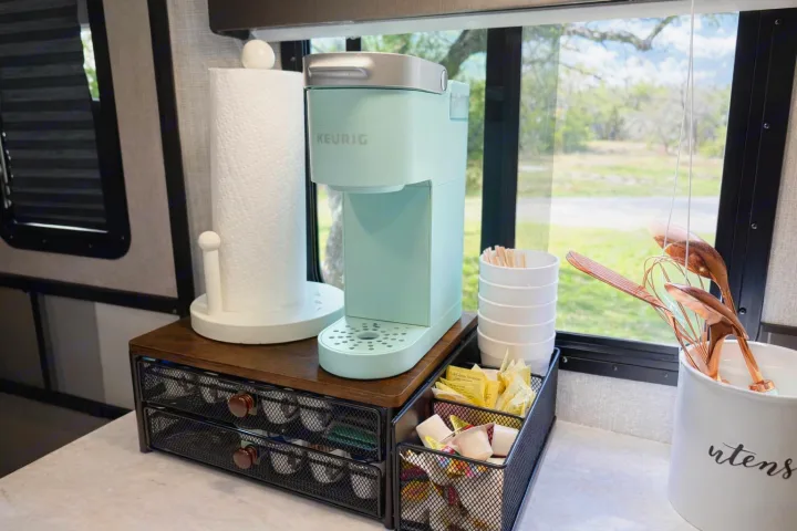 RV rental coffee station: a teal Keurig, K-cup organizer, paper towels, and coffee essentials neatly arranged on the counter.. Cruiser RV Radiance Ultra Lite 2020