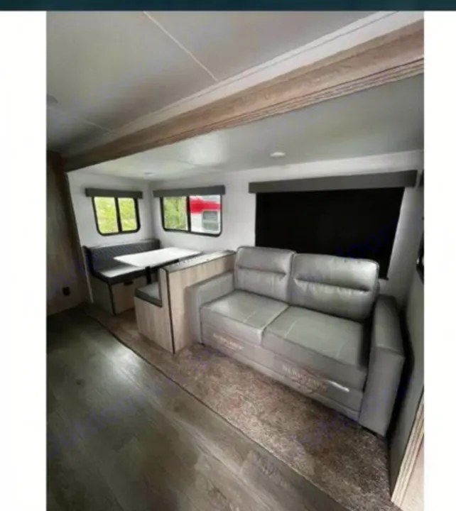 Modern rv rental interior with a comfy gray sofa, dinette, and large windows. Perfect for your next travel trailer adventure.. Riverside RV Intrepid 2023