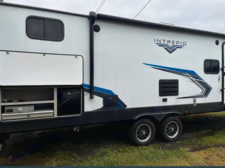 This white Intrepid travel trailer RV rental features an open outdoor kitchen with a grill and mini-fridge.. Riverside RV Intrepid 2023